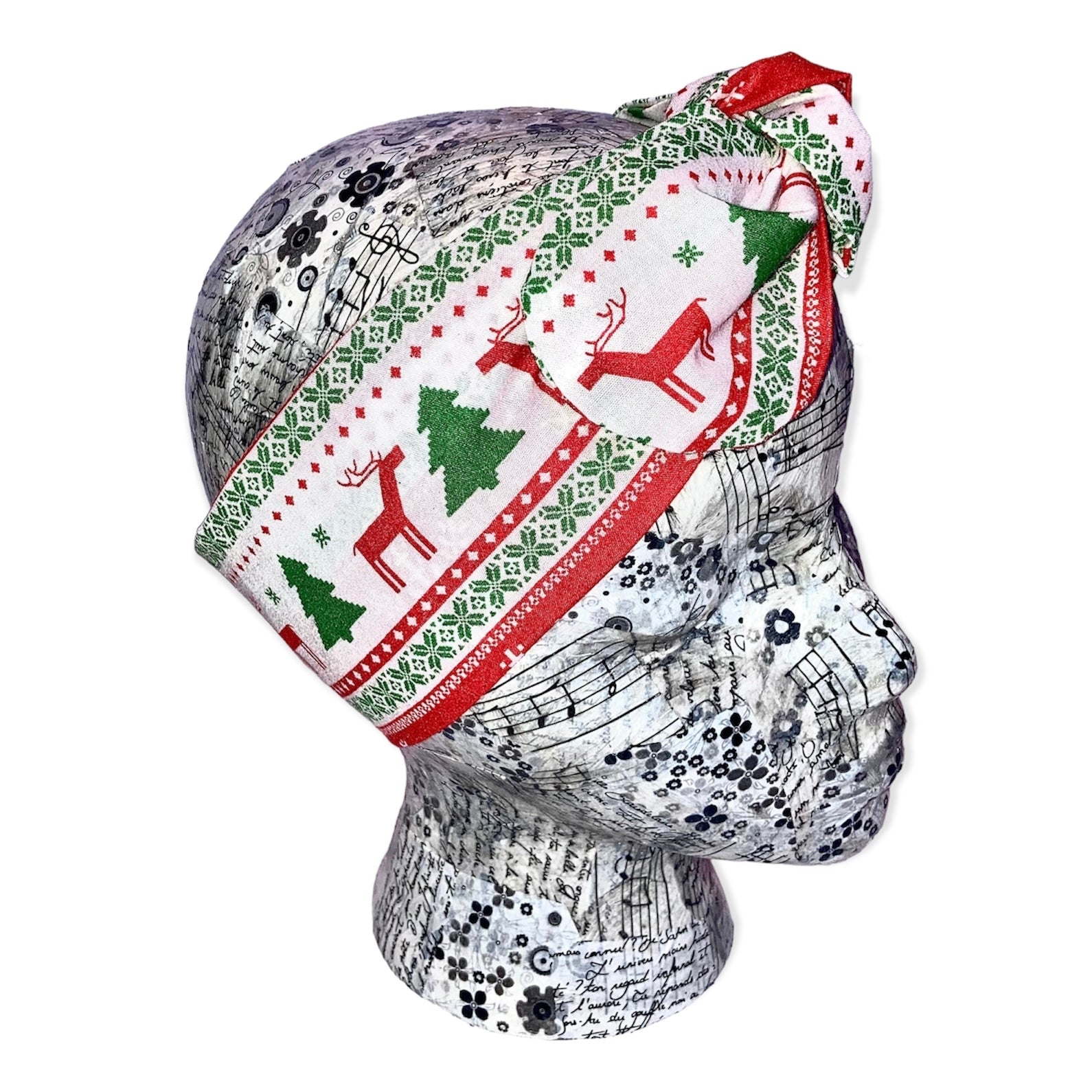 christmas headband in a traditional scandi christmas pattern. red reindeer, green trees, white background with red and green pattern border. Headbsnd is on a decorated polystyrene head and is tied on with a knotted bow towards the top